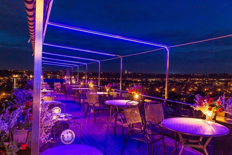 colorful light, round tables, chairs on a rooftop cafe