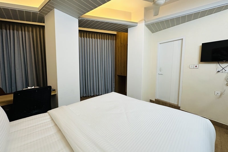 hotel room with white bed, brown wooden floor