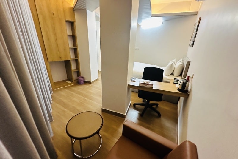 hotel room with white bed, brown wooden floor