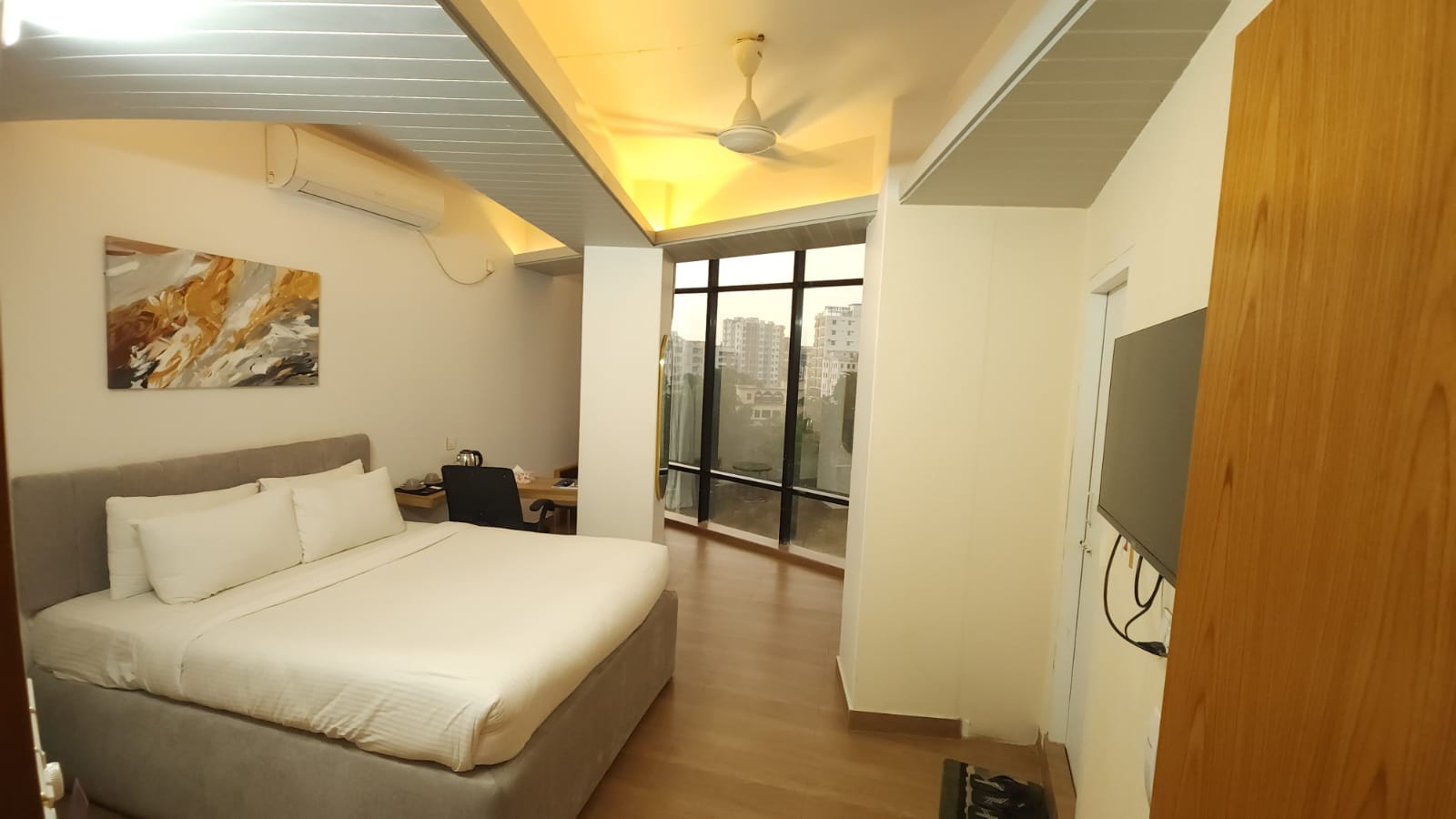 hotel room with white bed, brown wooden floor